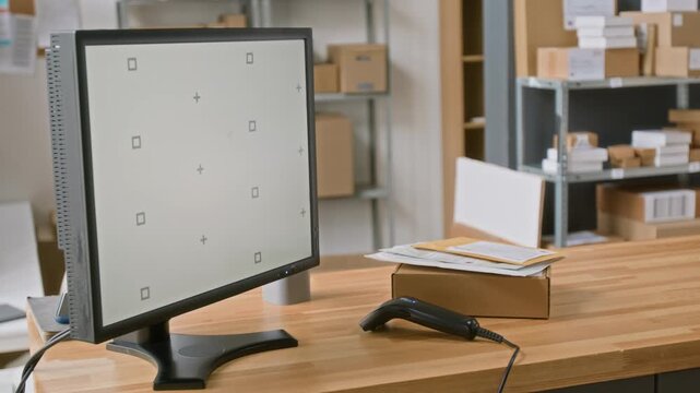 No people side shot of computer screen with blank screen, barcode scanner, cardboard parcel box and envelopes on counter of customer service agent at express delivery office. Template, copy space