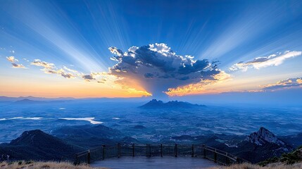 A breathtaking sunrise illuminates a vast landscape with dramatic crepuscular rays fanning out from behind clouds, viewed from a mountain overlook.
