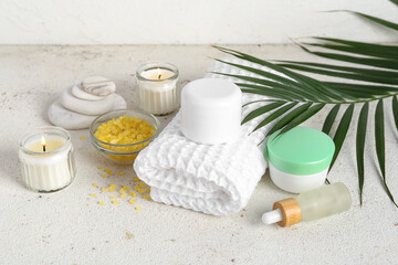 Composition with spa accessories, cosmetics and palm leaf on light table