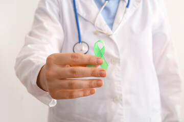 Female doctor holding green awareness ribbon, closeup. Mental Health Day