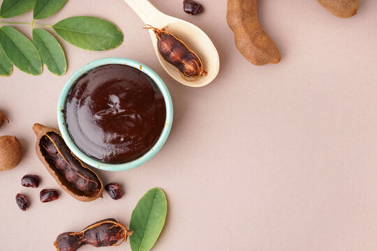 Bowl with tasty tamarind jam with fruits on beige background