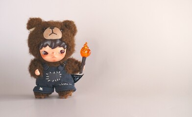 Turkey, October 19, 2025: Adorable doll dressed in a fluffy bear costume holds a small torch with autumn-themed decorations nearby. 