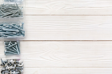 Packages with tap bolts, screws and chrome nuts on white wooden background