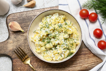 Bowl of tasty potato salad with dill, tomatoes and garlic on grey grunge background