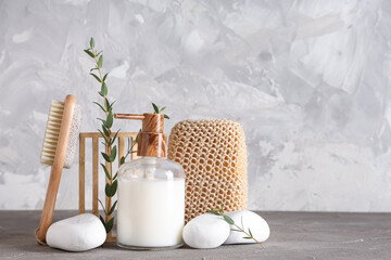 Composition with spa accessories, bottle of cosmetic product and eucalyptus branches on grunge background