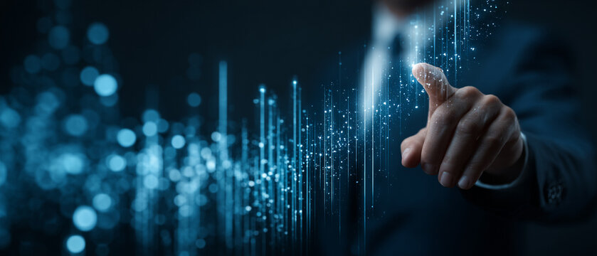 A businessman points towards a digital interface, showcasing futuristic technology concepts with glowing data visualizations and lines, symbolizing innovation and connectivity.