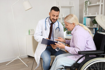 Obraz premium Male doctor working with mature woman in wheelchair at hospital
