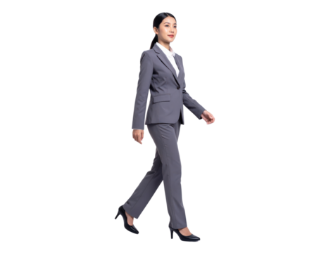 Confident young businesswoman walking with purpose in a professional grey suit.