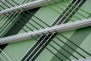 Close up of green metal pipes on modern building facade with geometric diagonal patterns.