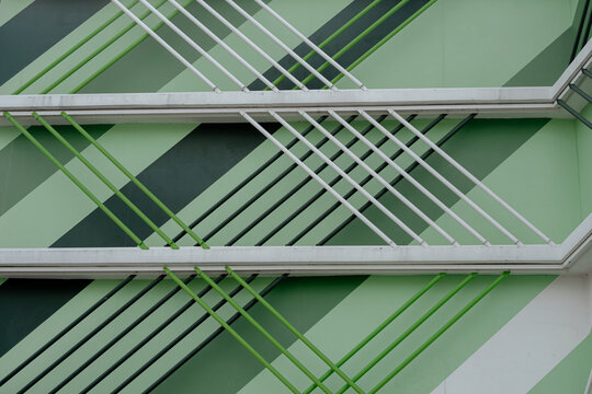 Modern architectural detail with green and white diagonal lines and pipes, geometric building design.
