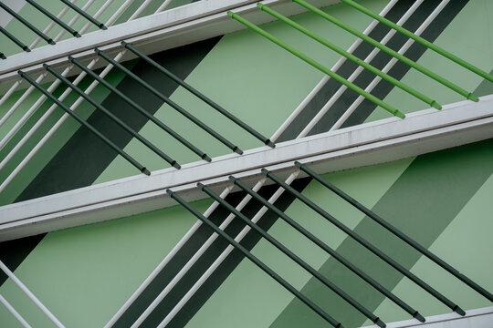 Close up of green metal pipes on modern building facade with geometric diagonal patterns.