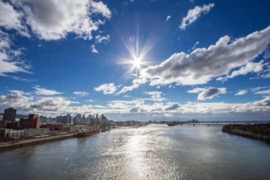 Wide view of a cargo ship at the industrial port of Montreal on the St Lawrence River, with the downtown skyline and business district visible behind in Quebec Canada, North America.