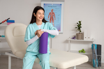 Female physiotherapist with foam roller  in rehabilitation center