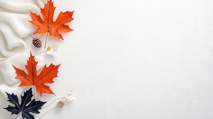 A flat lay composition featuring vibrant orange maple leaves, dark blue leaves, pinecones, and delicate white flowers against a white background with soft fabri