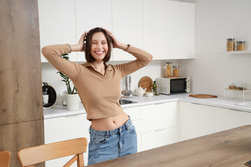 Young woman with headphones dancing in kitchen