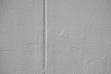 Gray rough stucco wall texture with a single vertical groove line, minimalist concrete background.