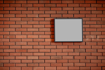 Blank rectangular frame on red brick wall, empty billboard mockup space for advertising.