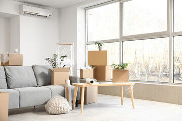 Sofa and table with cardboard boxes in room on moving day