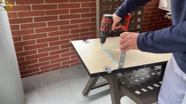 a cordless drill untightening a screw on a angle bracket on a wooden board, home improvement, weekend DIY