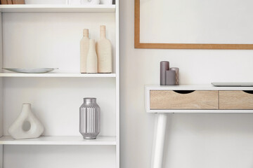 Shelf unit with stylish decor and grey candles on desk in light room
