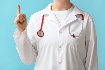 Female doctor pointing at something on blue background, closeup
