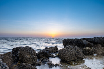 sunrise on the coast with limestone rocks in the foreground