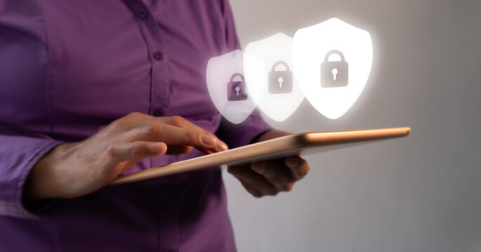 A woman is holding a tablet with a security icon on it. Concept of protecting something valuable or important
