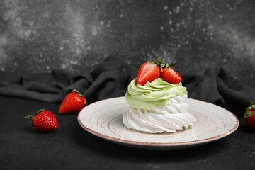 Plate of sweet Pavlova cakes with fresh strawberries on black background