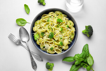Bowl of delicious conchigile rigate pasta with broccoli, cheese and basil leaves on white background