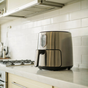 La cocina saludable: Una freidora de aire moderna sobre una encimera de m&aacute;rmol en una cocina de dise&ntilde;o