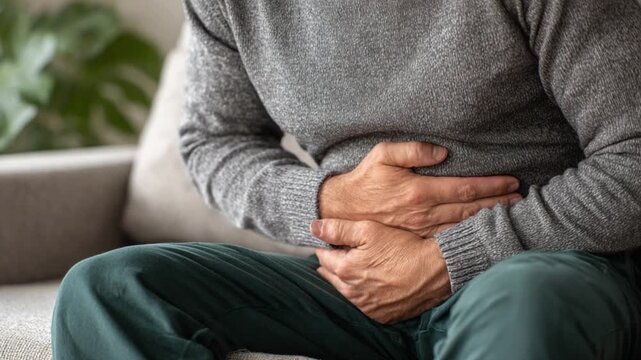   Stomach Pain: A person, experiencing intense abdominal discomfort, clutches his stomach in a visible sign of distress, reflecting a moment of vulnerability and discomfort. 