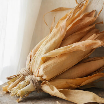 El coraz&oacute;n de la cosecha: Un ramo de mazorcas de ma&iacute;z secas atadas con yute sobre madera r&uacute;stica