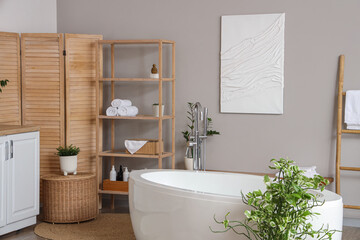 Bathtub, shelving unit and folding screen in interior of light bathroom