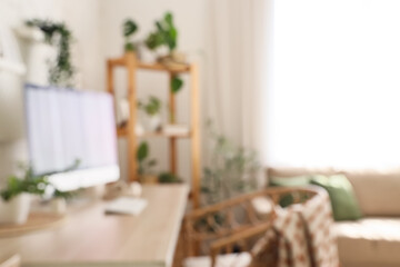 Blurred view of office with workplace, shelf unit and green plants