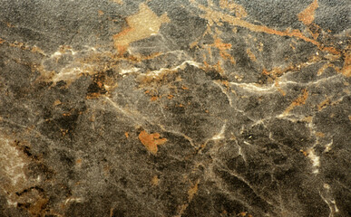 Dark gray marble, a natural stone with an orange spiderweb pattern, close-up.