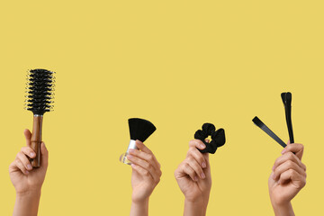 Female hands with different hairdresser's supplies on yellow background