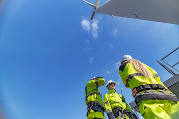 Fototapeta premium A team of engineers celebrates success after completing wind turbine maintenance at a wind farm. Renewable energy teamwork, green power, and sustainable energy practices in action.