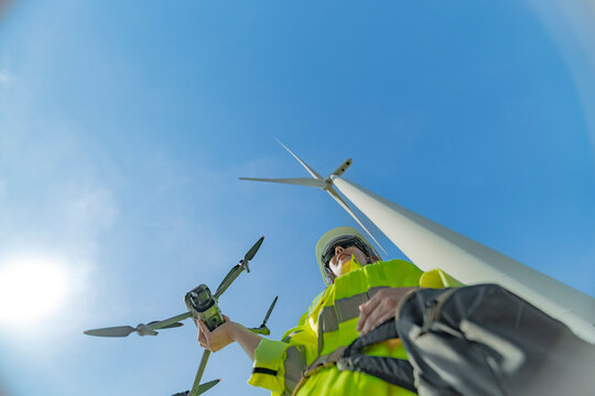 engineers conducting an aerial inspection of a wind turbine using a drone. The scene highlights modern technology’s role in renewable energy maintenance, showcasing collaboration and innovation.