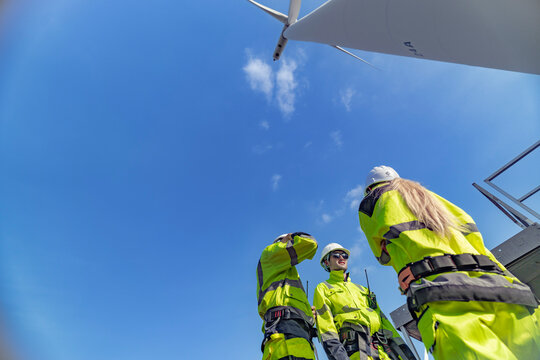 A team of engineers celebrates success after completing wind turbine maintenance at a wind farm. Renewable energy teamwork, green power, and sustainable energy practices in action.