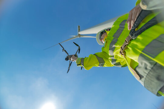 engineers conducting an aerial inspection of a wind turbine using a drone. The scene highlights modern technology’s role in renewable energy maintenance, showcasing collaboration and innovation. - Powered by Adobe