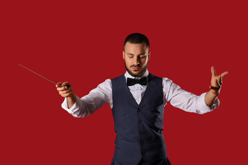 Young male conductor on red background © Pixel-Shot