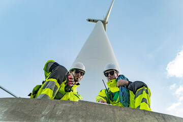 Team of engineers in reflective work suits join hands to inspect and demonstrate their work and...