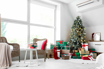 Interior of light bedroom with Christmas tree, presents and armchairs
