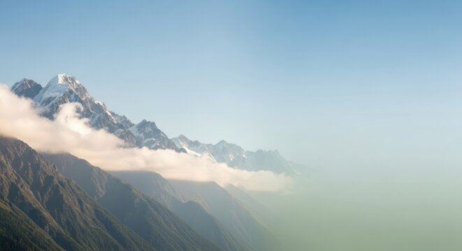 Scenic panorama showcasing snow-capped mountain range partially veiled in fog