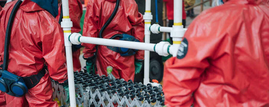 Hazmat team members in protective suits working with equipment - Powered by Adobe