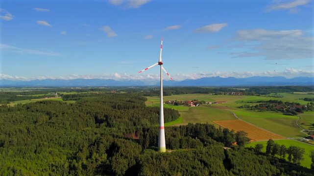 Aerial view of wind turbine in Bavaria, Ebersberg region, Germany. Luftaufnahme einer Windturbine vor dem Hintergrund der Alpen in Bayern, Deutschland. Wind turbine on golf course overlooking alps. 