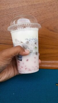 Hand holding creamy es teler in plastic cup