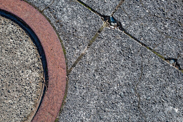 A section of the rusty iron ring around a manhole cover on pavement