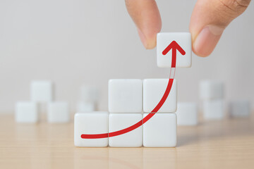 Business growth, progress or success concept. Dice with a growing graph arranged in stair shape and a man is holding the top one.
