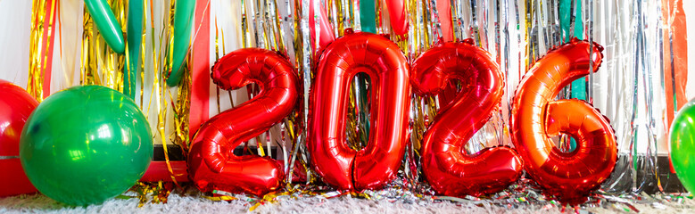 Red foil balloons forming number 2026 with colorful party decorations